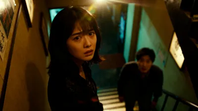 階段の下で初めてのお客様を待つ、緊張した表情の里奈